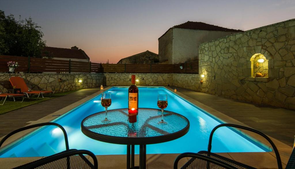 a table with wine glasses next to a swimming pool at Skandalis Apartments in Chorafakia