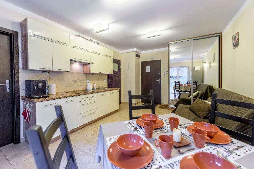 a kitchen and a living room with a table and chairs at Apartament Kawowy - 5D Apartamenty in Świeradów-Zdrój