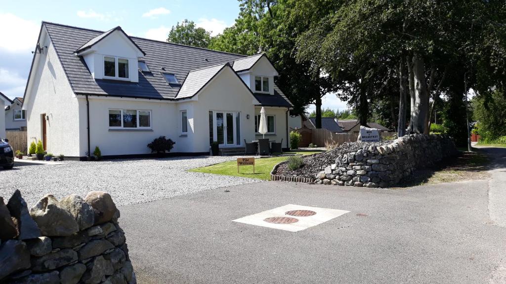 a white house with a stone wall in front of it at The Willows in Beauly