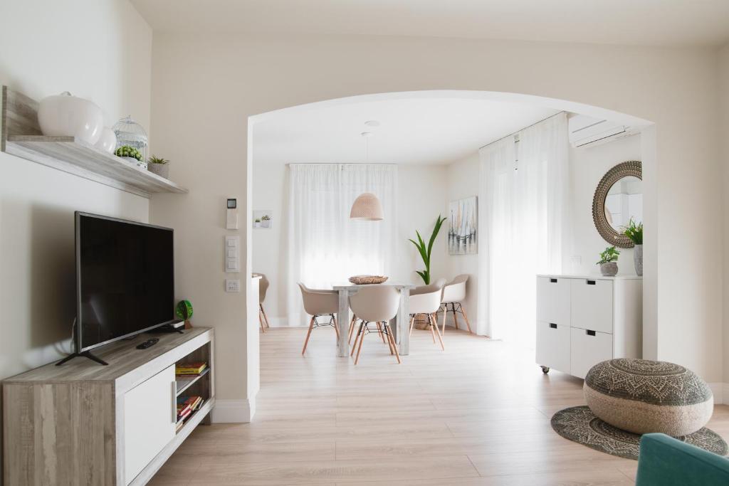 uma sala de estar branca com uma televisão e uma mesa em Apartamentos Hotel Pirineos em Figueres