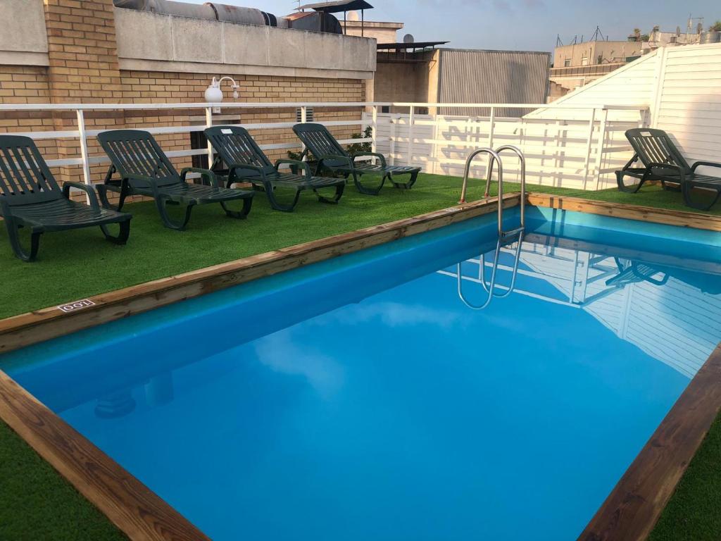 a swimming pool with chairs and a swing at Apartamentos Santi in Lloret de Mar