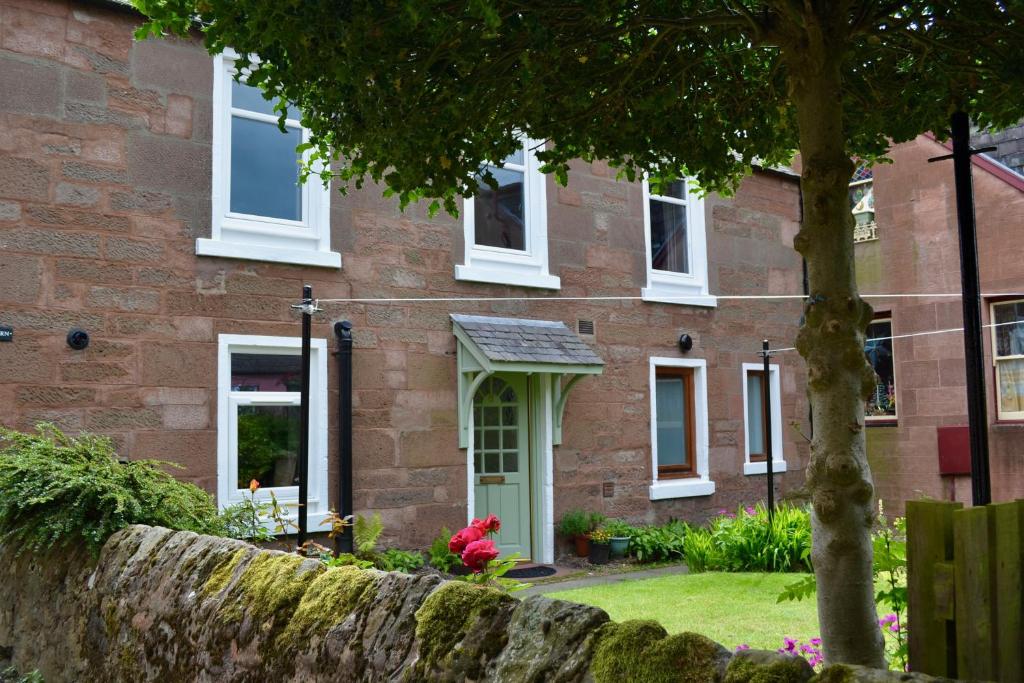 a brick house with white windows and a stone wall at Caliburn in Alyth