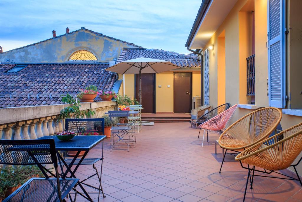 a patio with chairs and tables and an umbrella at Residence Studio Vita in Bologna