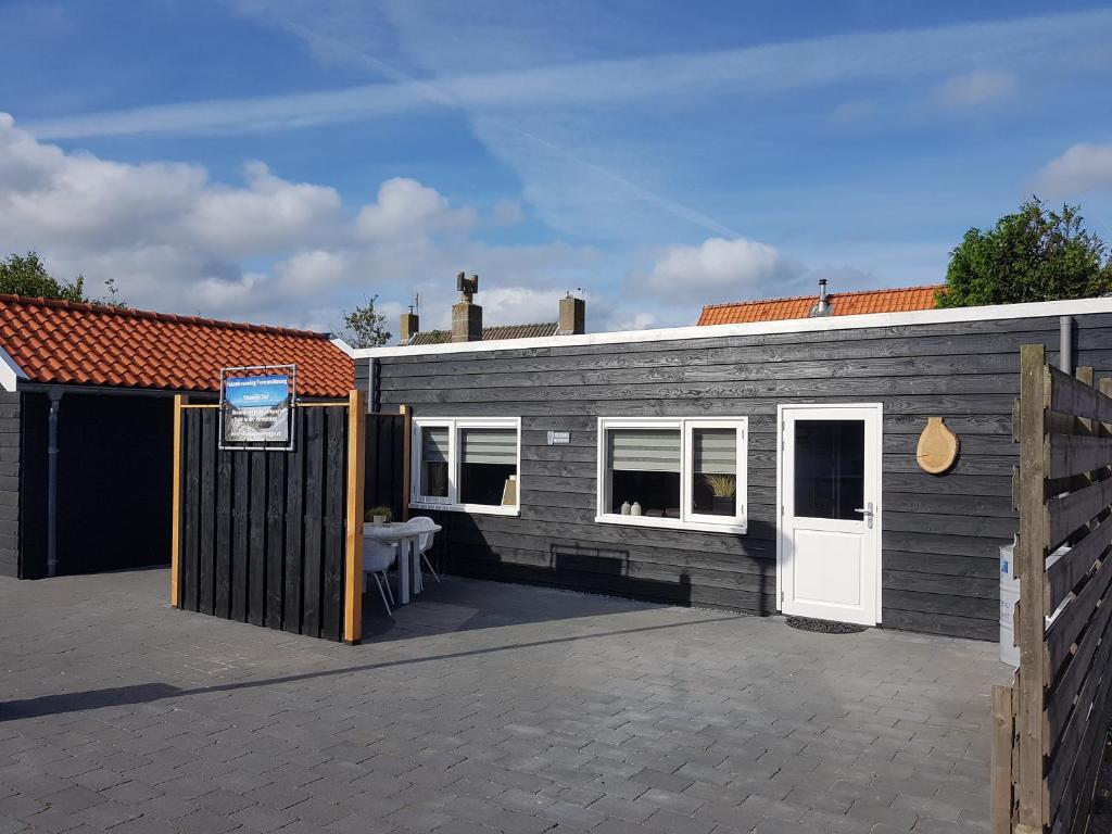 a grey brick building with a white door at Vitamine Zee in Petten
