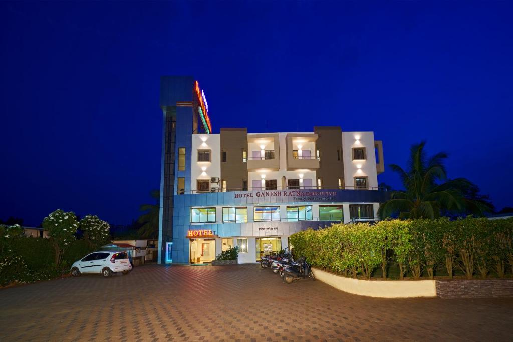 a building with a car parked in front of it at Hotel Ganeshratna Executive Kolhapur in Kolhapur