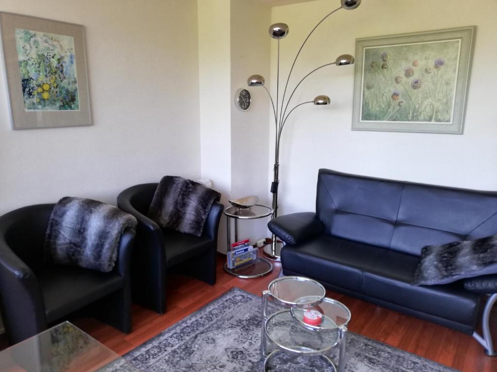 ein Wohnzimmer mit zwei schwarzen Sofas und einem Tisch in der Unterkunft Saskia in Zoutelande