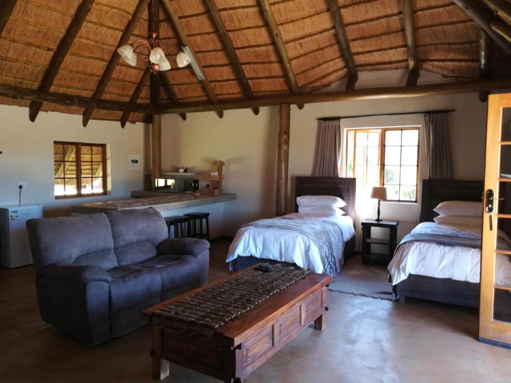 a living room with two beds and a couch at African Flair Country Lodge in Piet Retief
