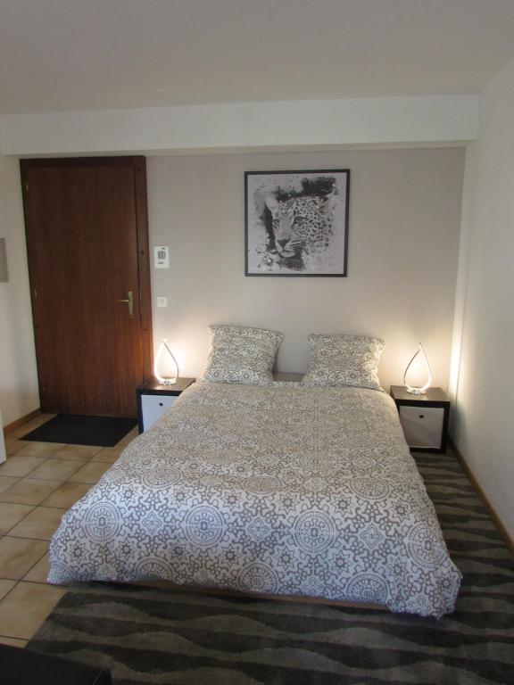 a bedroom with a large bed with two lamps at Studio à Sion in Sion