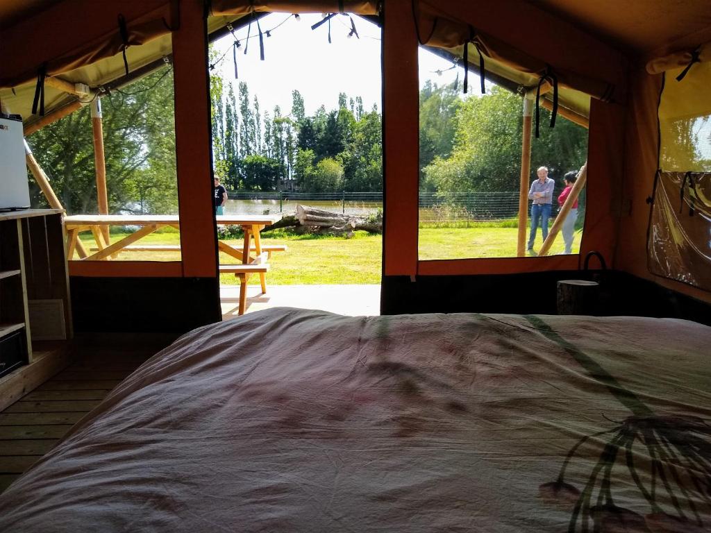 a room with a bed in a tent with a window at Rosy Garden in Lichtervelde