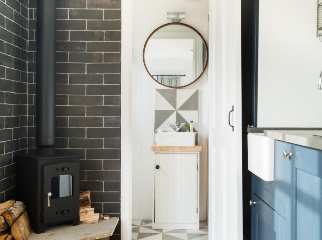 a living room with a fireplace and a mirror at Purbeck Shepherd Huts in Worth Matravers