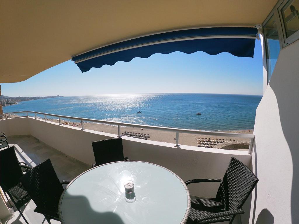 balcón con mesa y sillas y vistas al océano en Beach Front Penthouse - Fuengirola, en Fuengirola
