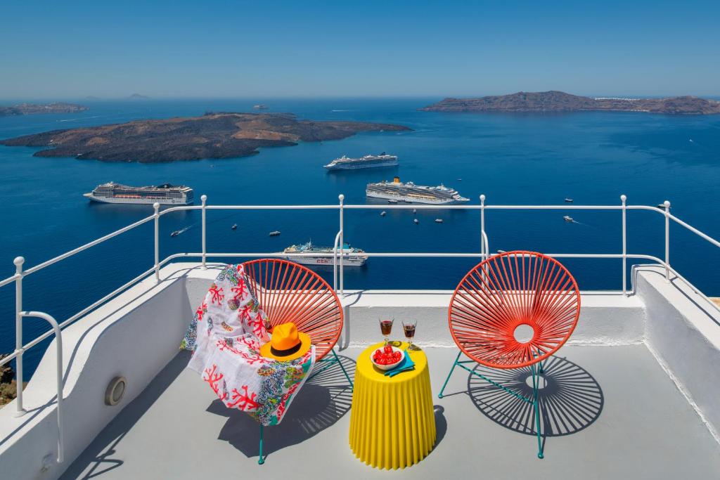 a balcony with two chairs and a view of the ocean at Barocco Bello Villa in Fira