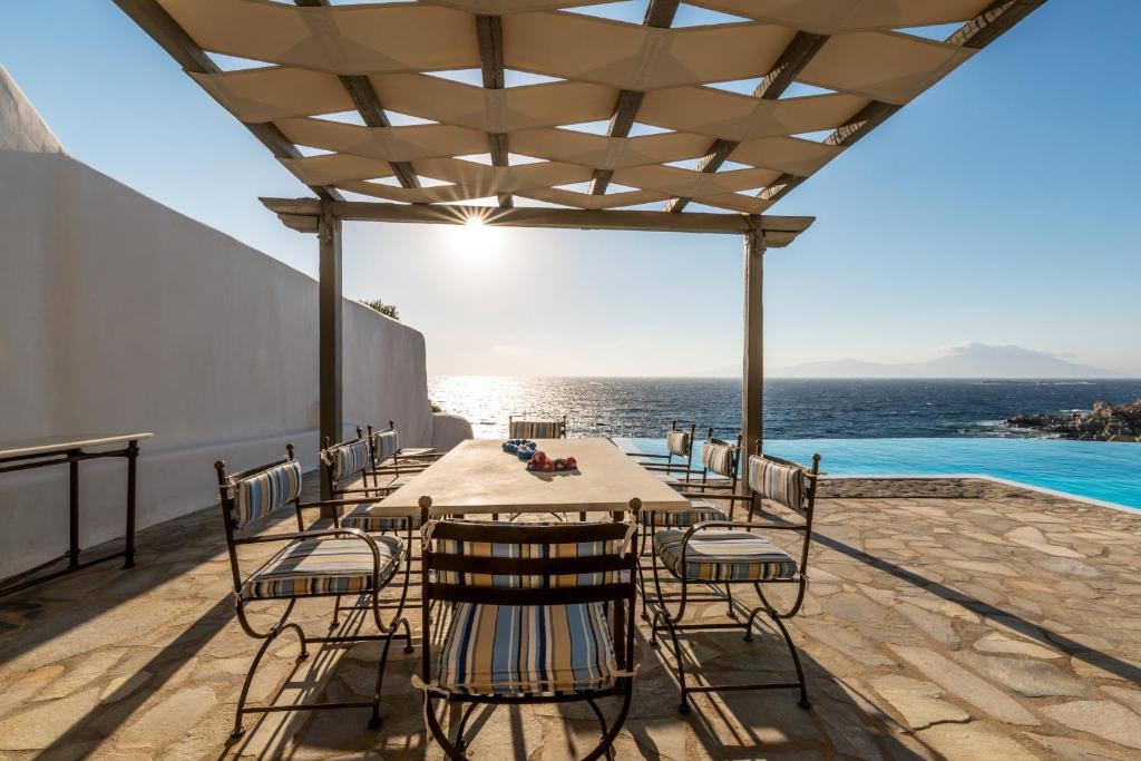 een tafel en stoelen op een patio met uitzicht op de oceaan bij Villa Coventina, Ornos - Cavo Delos, Mykonos in Agios Ioannis Mykonos