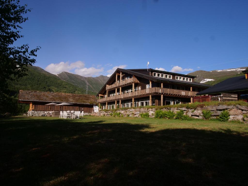 a large wooden building with mountains in the background at Blåtind Boutique Hotel in Stordal