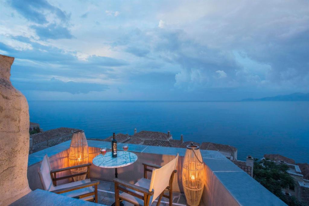a patio with a table and chairs and the ocean at Casa Rodanthi - Luxury Castle Residence in Monemvasia