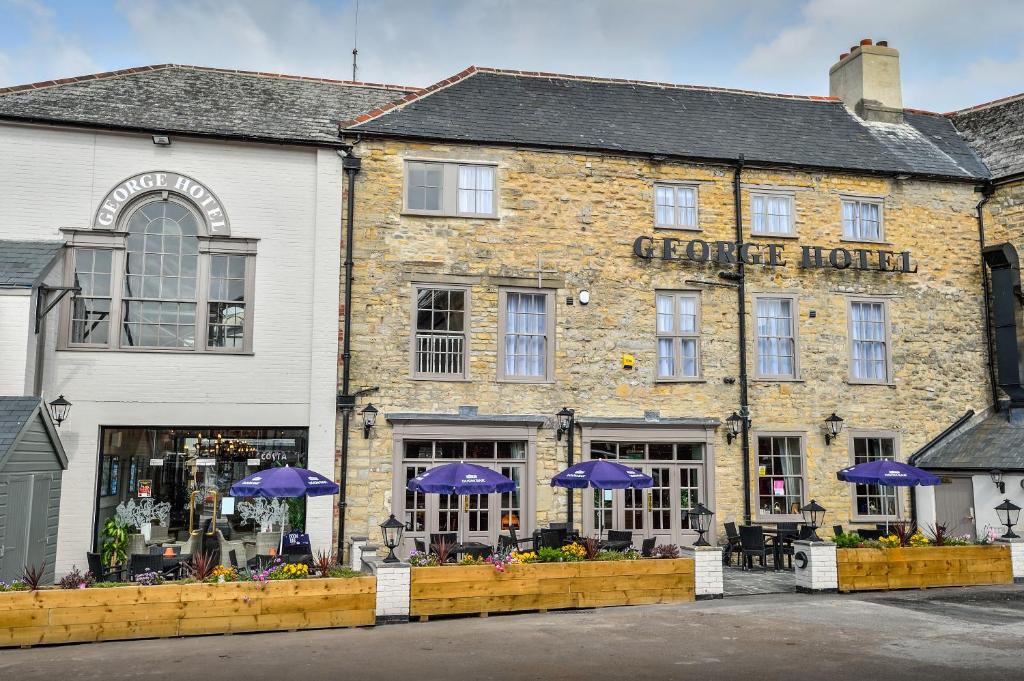 a brick building with purple umbrellas in front of it at The George Hotel in Axminster