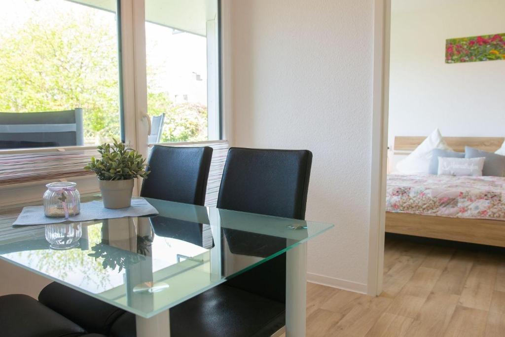 a glass table and two chairs in a room with a bed at Haus-Strandburg-Sanddorn in Dahme