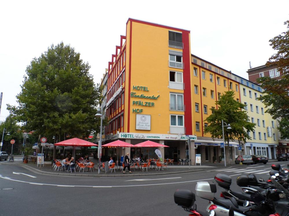 ein Gebäude mit Tischen und roten Sonnenschirmen auf einer Stadtstraße in der Unterkunft Hotel Continental Koblenz in Koblenz