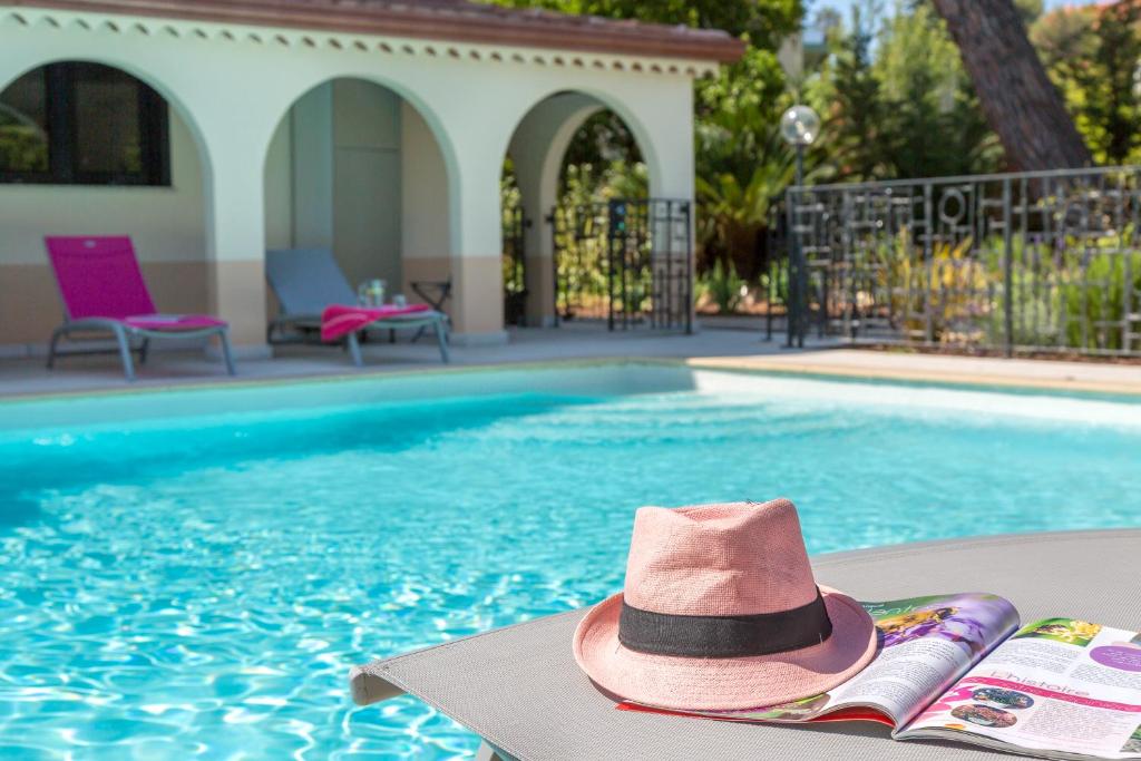 un cappello rosa seduto su una sedia accanto alla piscina di Ancre du Cap a Antibes