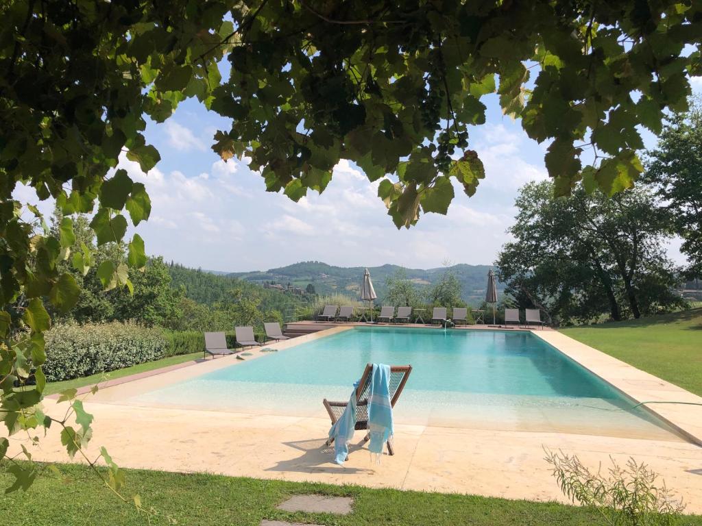 a swimming pool with chairs and a view of a hill at Villa Rignana in Greve in Chianti