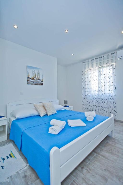 a white bedroom with a blue bed with towels on it at Apartments Magdalena in Hvar