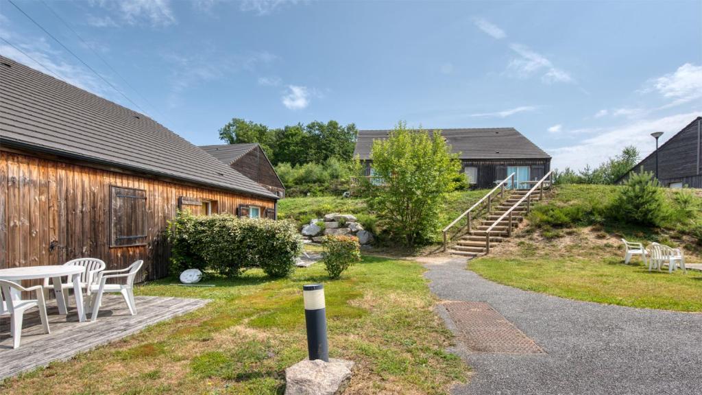 a backyard with a table and chairs and a building at Vacancéole - Residence le Domaine du Bosquet in Égletons