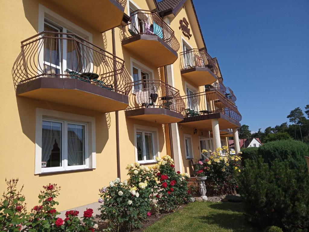 a building with balconies and flowers in a yard at Willa ANNA in Pustkowo