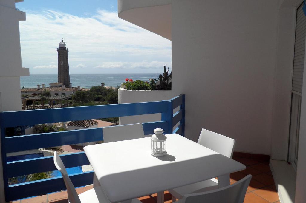 een witte tafel en stoelen op een balkon met een vuurtoren bij El FARO 2 in Estepona