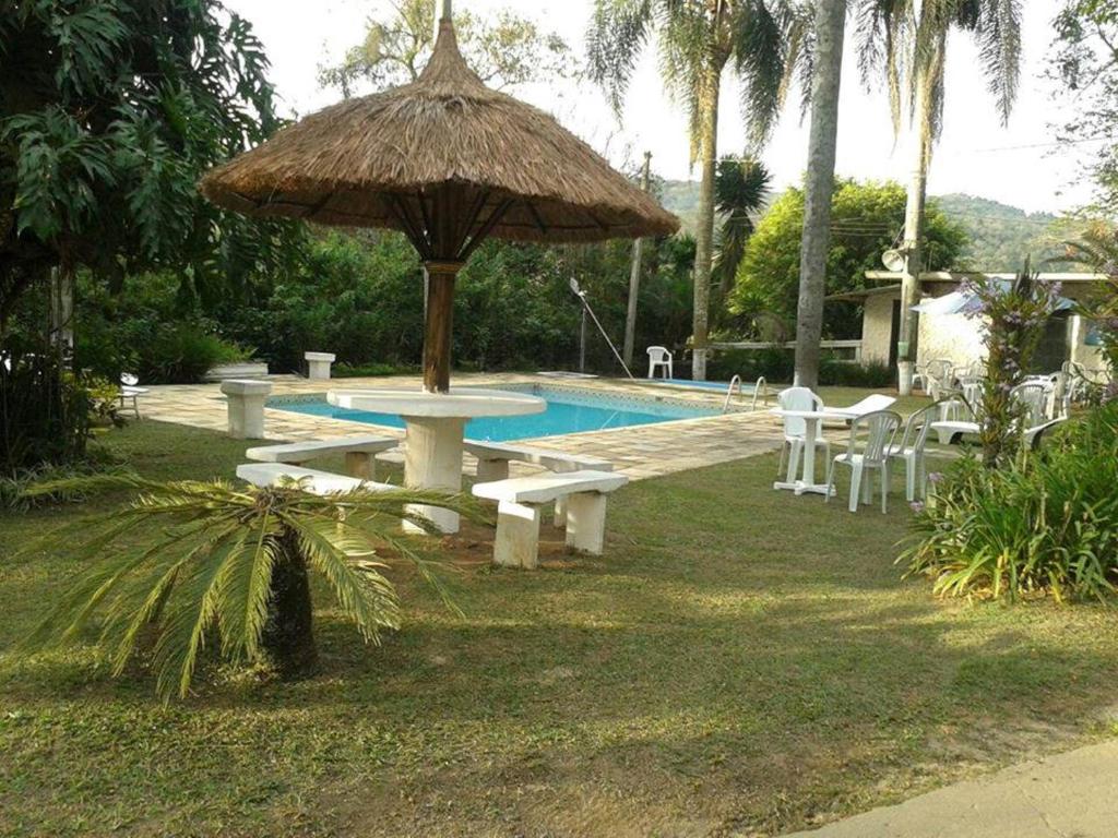 uma piscina com uma mesa de piquenique e um guarda-sol em Hotel Fazenda Bandeirantes em Ibiúna