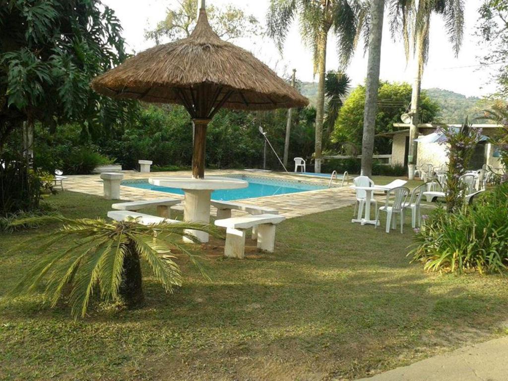 una piscina con una mesa de picnic y una sombrilla en Hotel Fazenda Bandeirantes, en Ibiúna