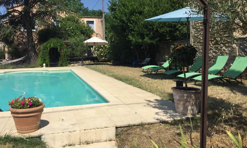 a swimming pool with a patio and an umbrella at Le Petit Jeu Grignan in Grignan