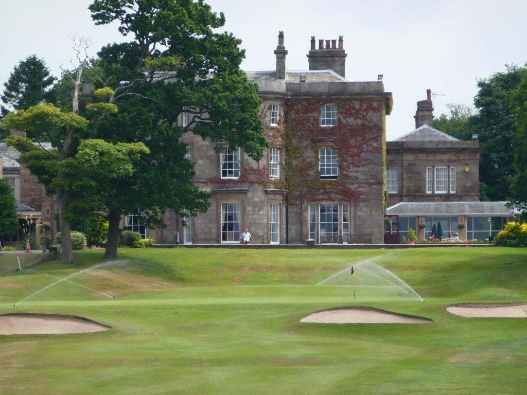 a view of a golf course with a house in the background at Shaw Hill Hotel Golf And Country Club in Chorley