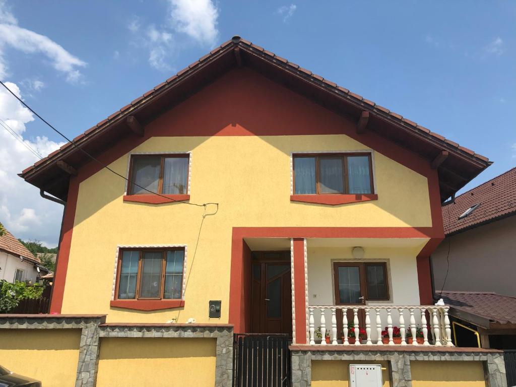 a yellow and orange house with a balcony at Casa Flori in Călimăneşti