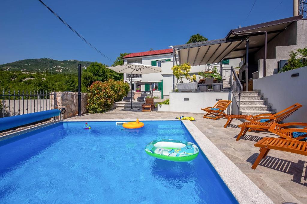 a swimming pool with a green boat in a backyard at Villa LETA, luxurious 5 stars villa in a green oasis with fitness, heated pool, playground & barbecue, Kvarner in Hreljin