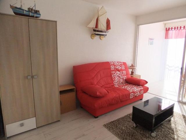 a living room with a red couch and a cabinet at residence Les Canaries in Le Pouliguen