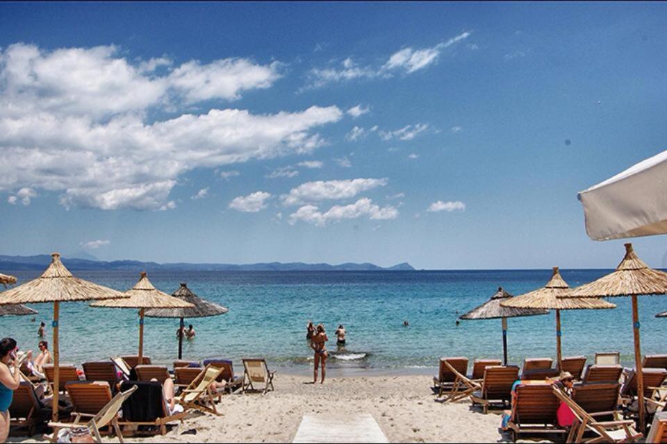 a beach with chairs and umbrellas and the ocean at Apartment by the beach - Nei Epivates in Neoi Epivates