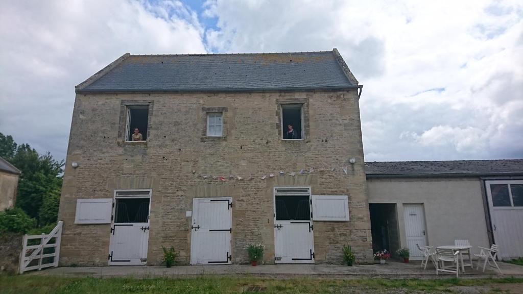 a brick building with white doors and a table at Boutons d'or in Tierceville