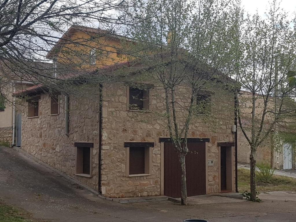 Casa Rural El Retiro de los Casasola في Establés: مبنى من الطوب القديم وامامه شجرة