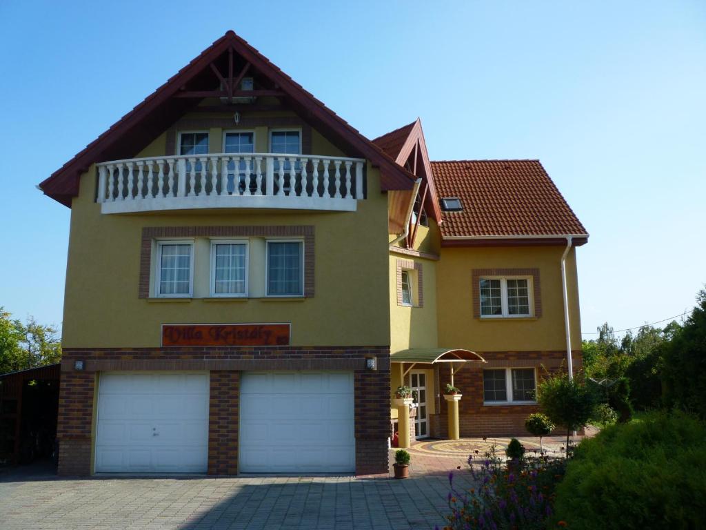 una casa amarilla con dos puertas de garaje delante de ella en Kristály Panoráma Villa, en Balatonfüred