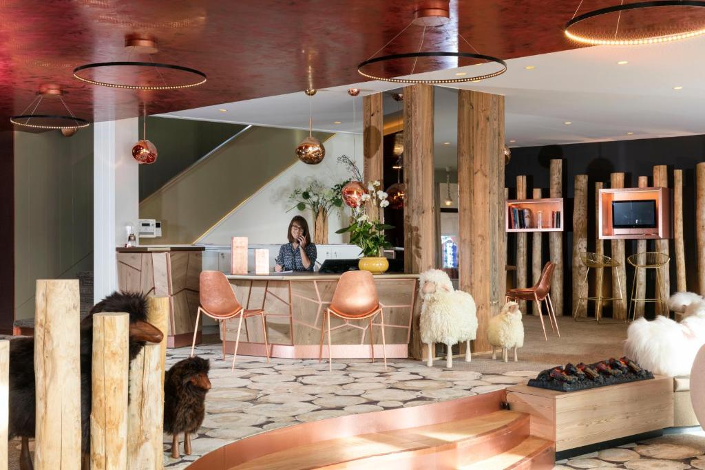 a woman sitting at a desk in a room with sheep at Grandes Rousses Hotel & Spa in L'Alpe-d'Huez