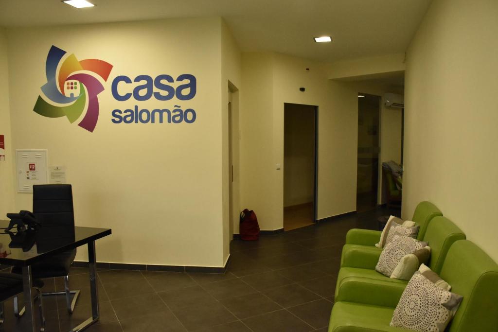 ein Wartezimmer mit grünen Sofas und einem Schild an der Wand in der Unterkunft Casa Salomão in Termas de Sao Pedro do Sul