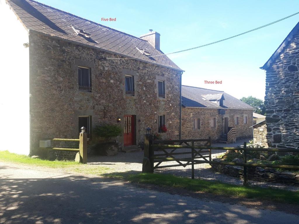 un bâtiment en pierre avec une porte rouge et une grange dans l'établissement Les Gites Audrain, à Plussulien