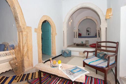 a living room with two arches and a green door at Dar Tenast in Houmt Souk