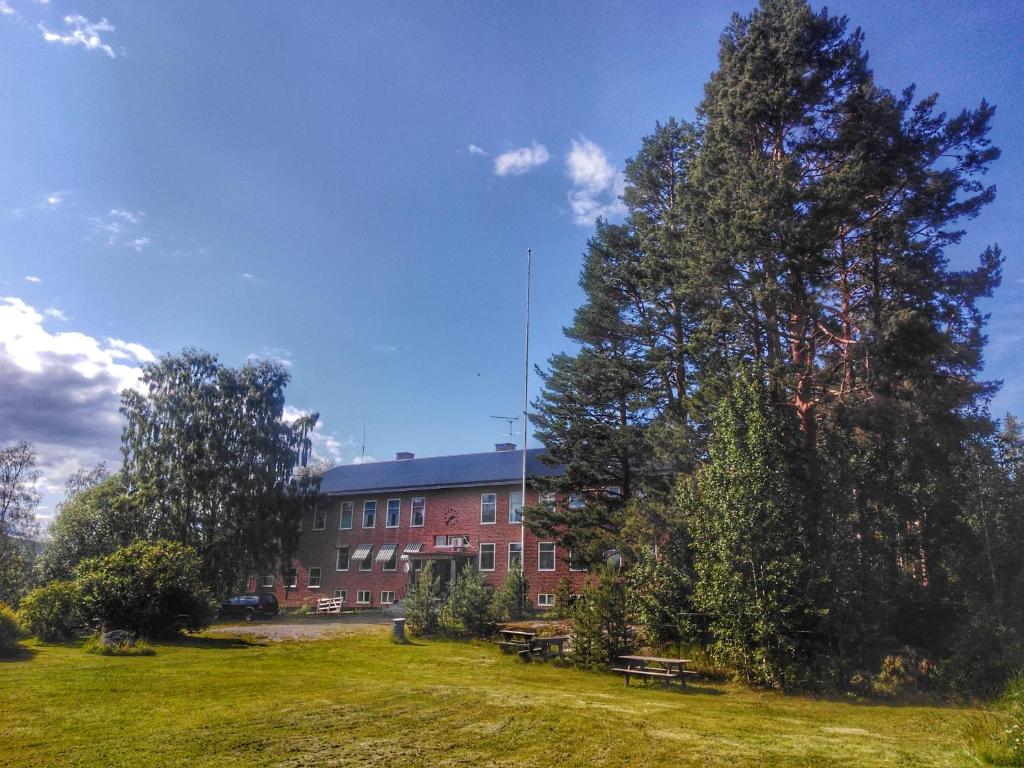 a building with a tree and benches in front of it at B&B Gillhov & Camping in Svenstavik