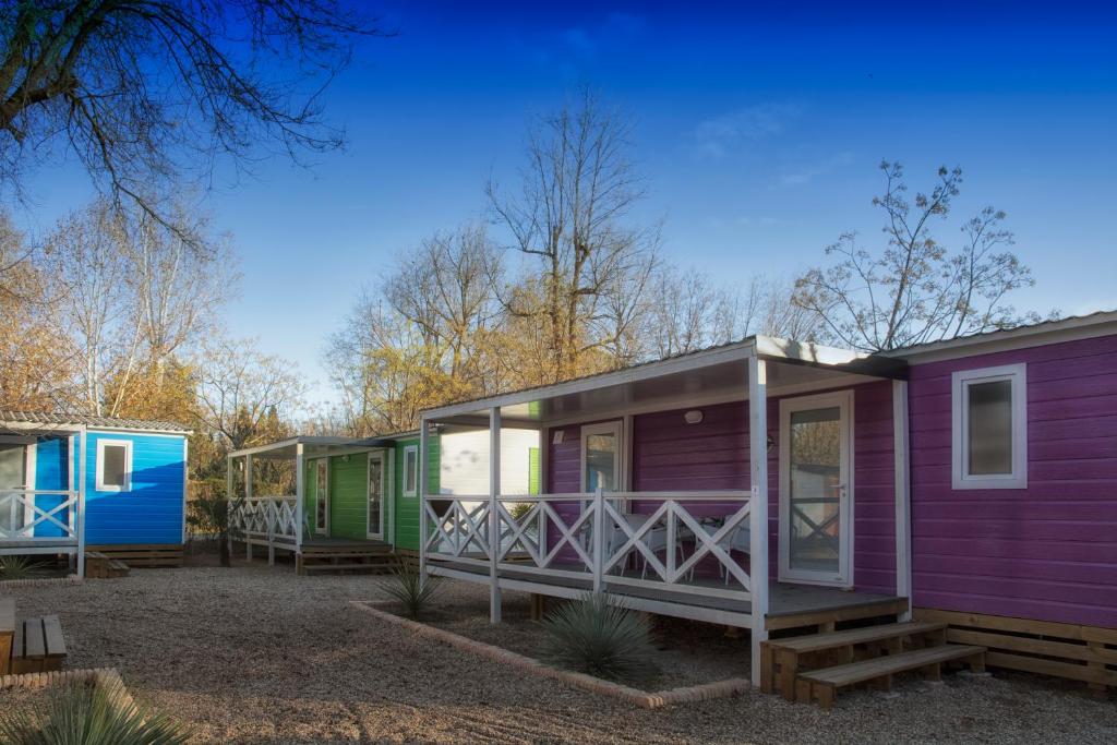 una fila de coloridas casas móviles en un parque en Aranjuez Camping & Bungalows en Aranjuez