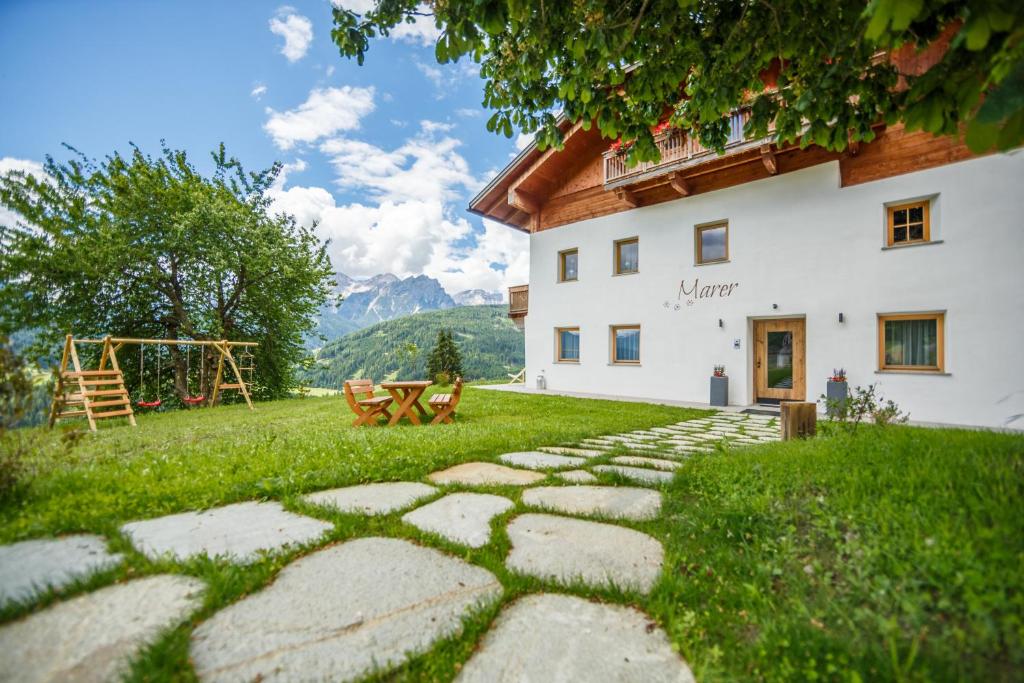 um caminho de pedra em frente a uma casa com um parque infantil em Agriturismo MARER Urlaub auf dem Bauernhof em Villabassa