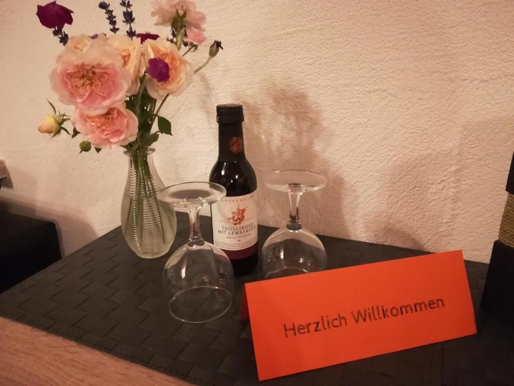 zwei Flaschen Wein und zwei Gläser auf einem Tisch mit Blumen. in der Unterkunft Sonnige Zimmer in Eberhardzell