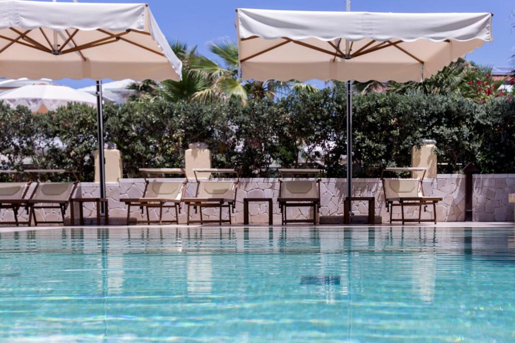 a pool with tables and chairs and umbrellas at Villaggio Tramonto in Capo Vaticano