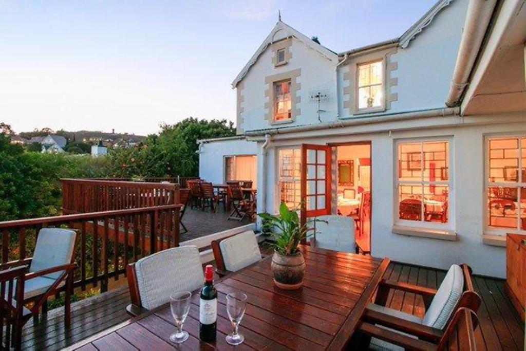 a deck with a wooden table and chairs on a balcony at Knysna Manor House in Knysna