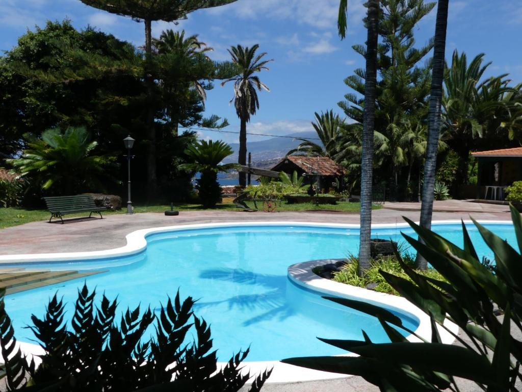 a swimming pool with palm trees and a bench at Finca San Antonio in Los Realejos